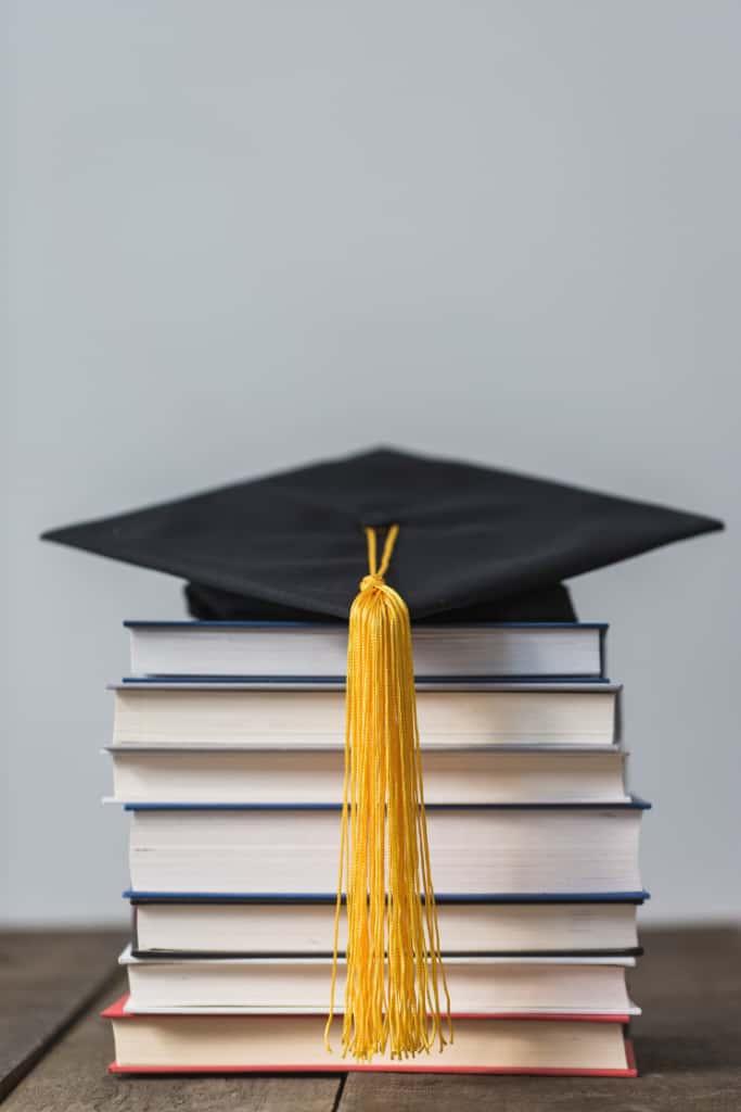 A graduation cap with a gold tassel resting on a stack of books