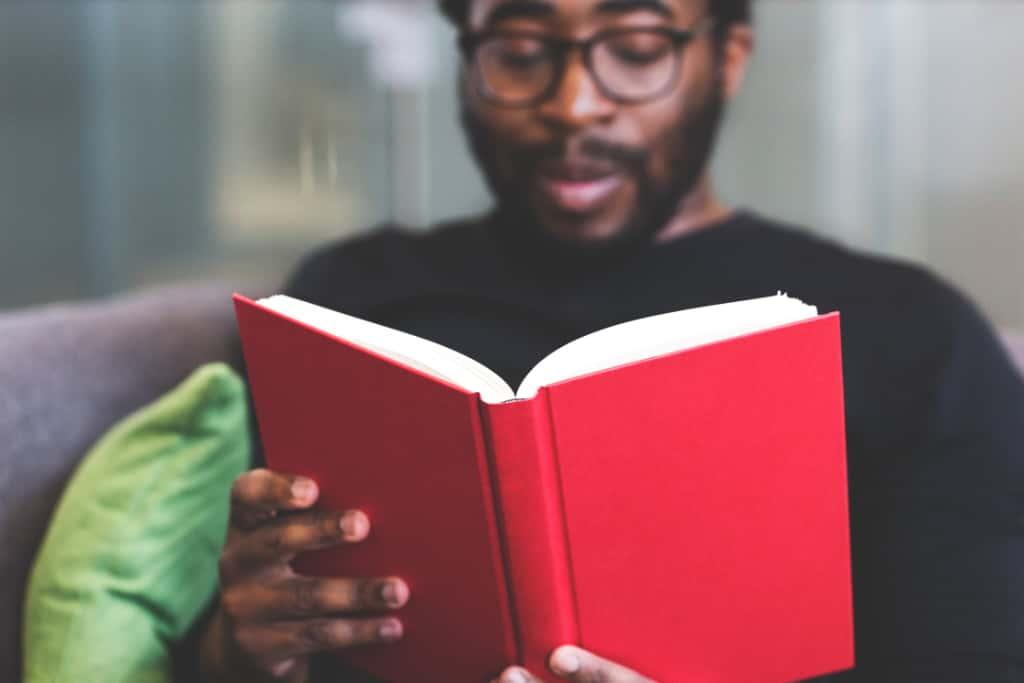 A learner reading a book with a red cover