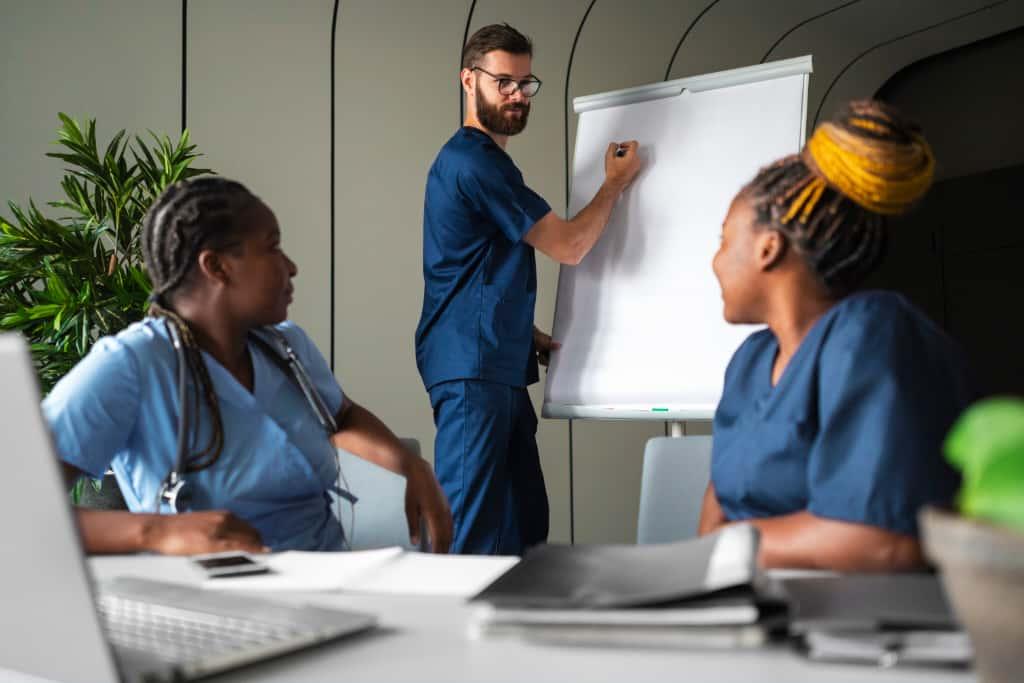 Care workers in uniform in a training session with a tutor at a flip chart
