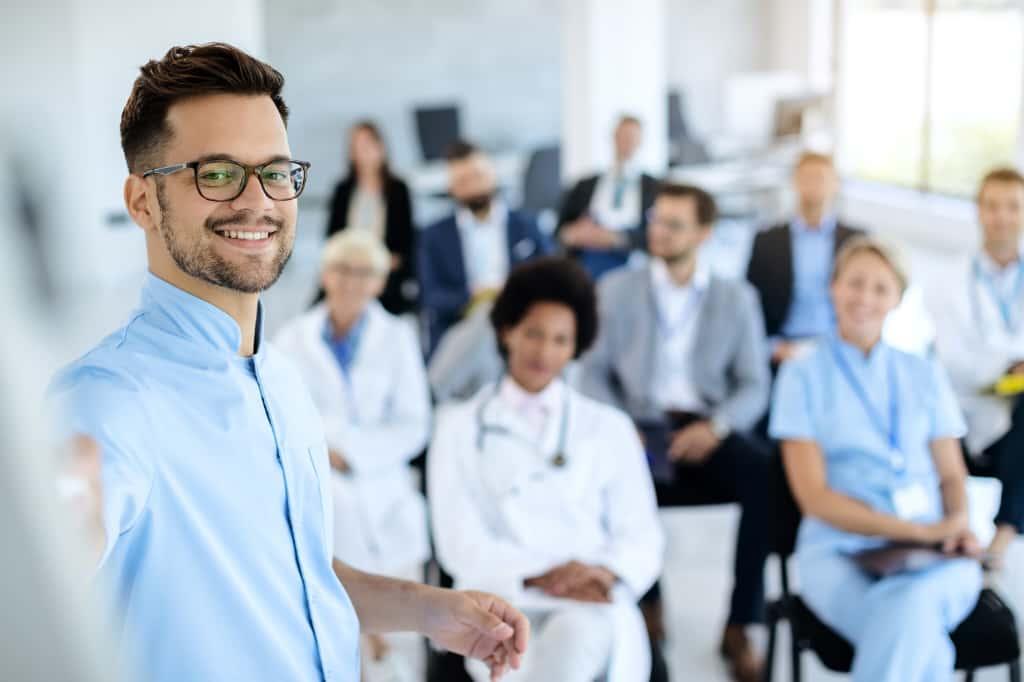 A confident healthcare leader standing in front of a team of staff